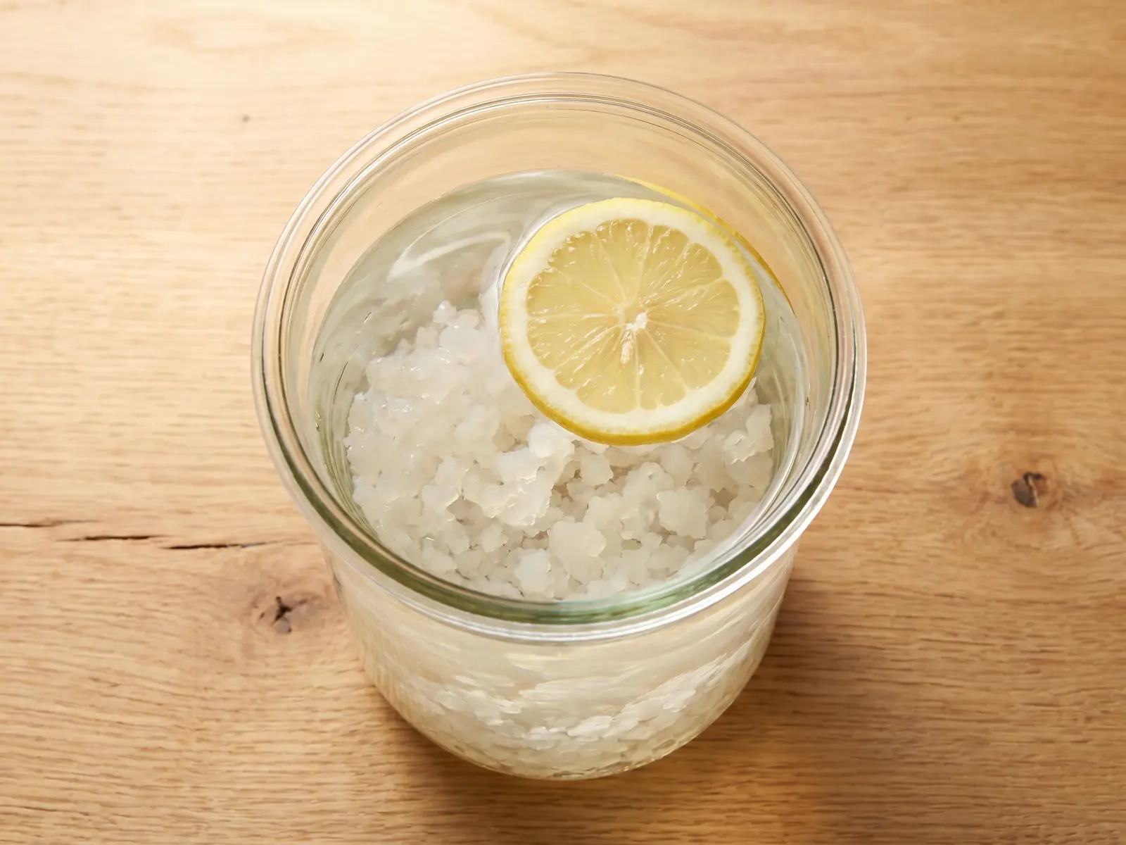 tibicos per kefir d acqua Barattolo visto dall’alto con acqua, grani di kefir e una fetta di limone sulla superficie.