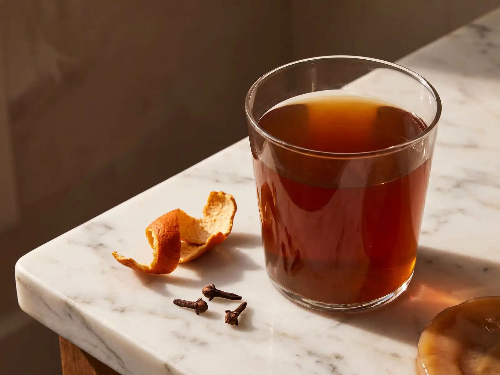 kombucha calorie Kombucha ambrata servita con chiodi di garofano e scorza d’arancia secca su marmo bianco.
